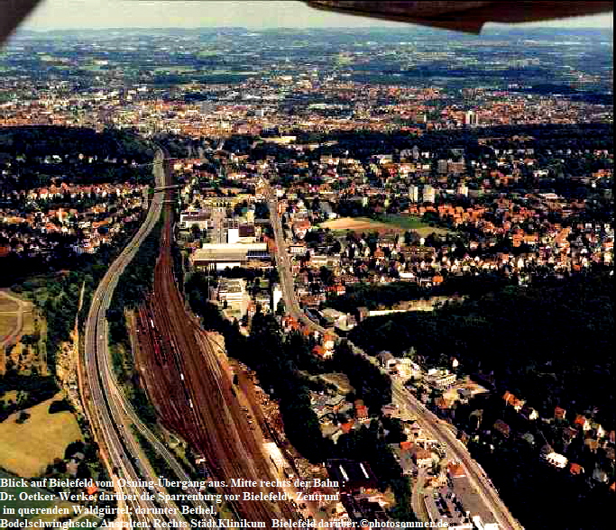 Blick auf Bielefeld vom Osning-bergang aus. Mitte rechts der Bahn : 
Dr. Oetker-Werke, darber die Sparrenburg vor Bielefeld - Zentrum 
 im querenden Waldgrtel; darunter Bethel, 
Bodelschwinghsche Anstalten. Rechts Stdt.Klinikum  Bielefeld darber.photosommer.de